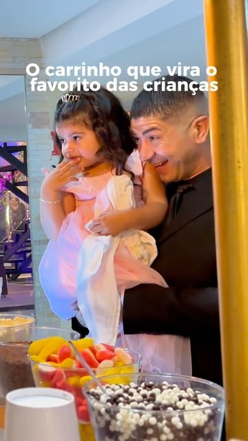 Pai segurando a filha diante do carrinho com acompanhamentos